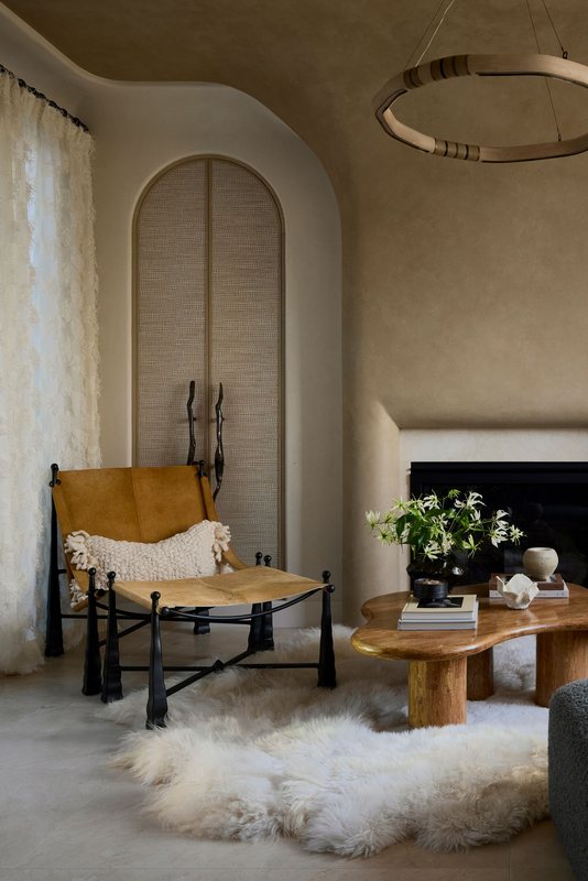 Sitting area with a suede sling chair beside the fireplace